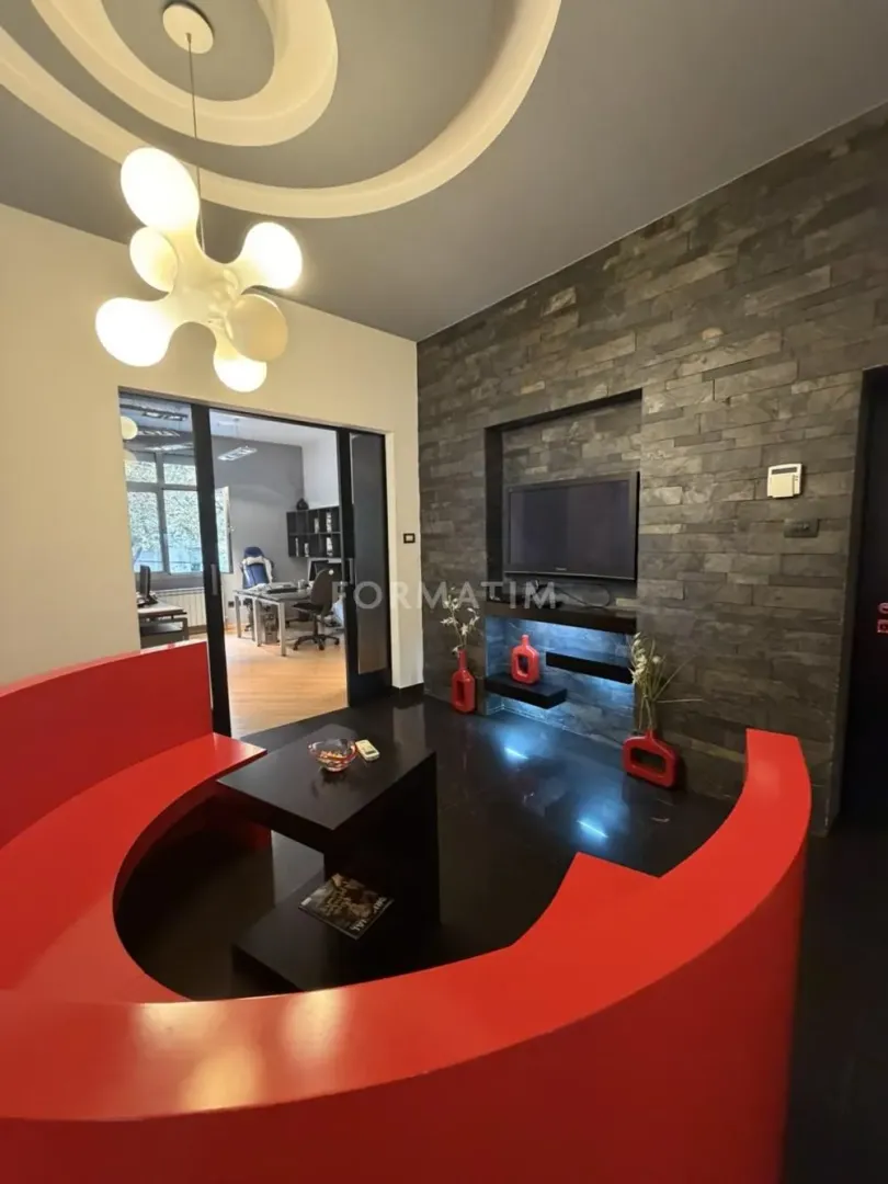 Living room with a red semicircular sofa and a stone-clad accent wall.
