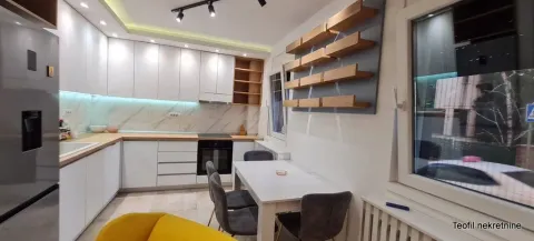 Moderna kuhinja sa belim elementima, ugradnim uređajima i trpezarijskim stolom. - image 7