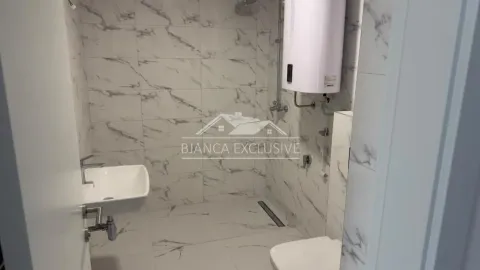 Manje kupatilo obloženo keramičkim pločicama sa mermernim dezenom, umivaonikom i tuš kabinom. - image 6