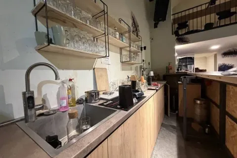 Kitchen area with a sink, countertop, and glass shelving on the wall. - image 9