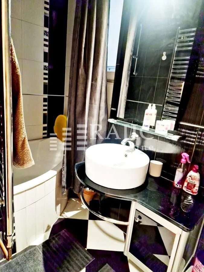 Modern bathroom with a sink, shower cabin, and black and white tiles.