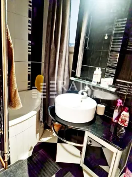 Modern bathroom with a sink, shower cabin, and black and white tiles. - image 10