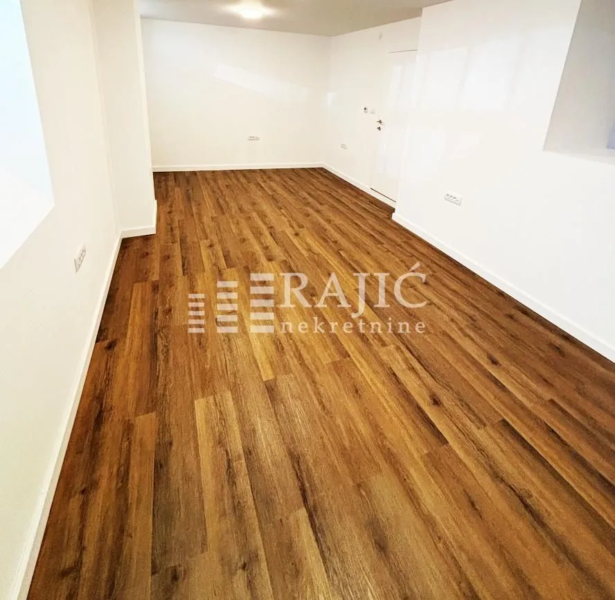 Empty room with laminate flooring and white walls.