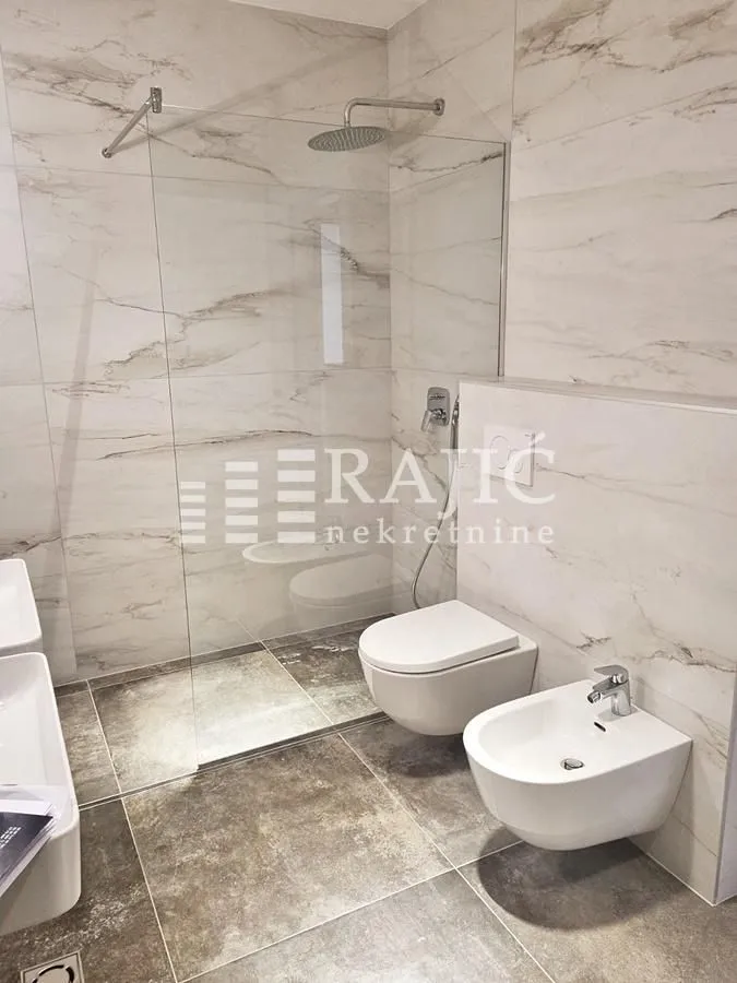 Modern bathroom with walk-in shower, sanitary ware, and marble tiles.