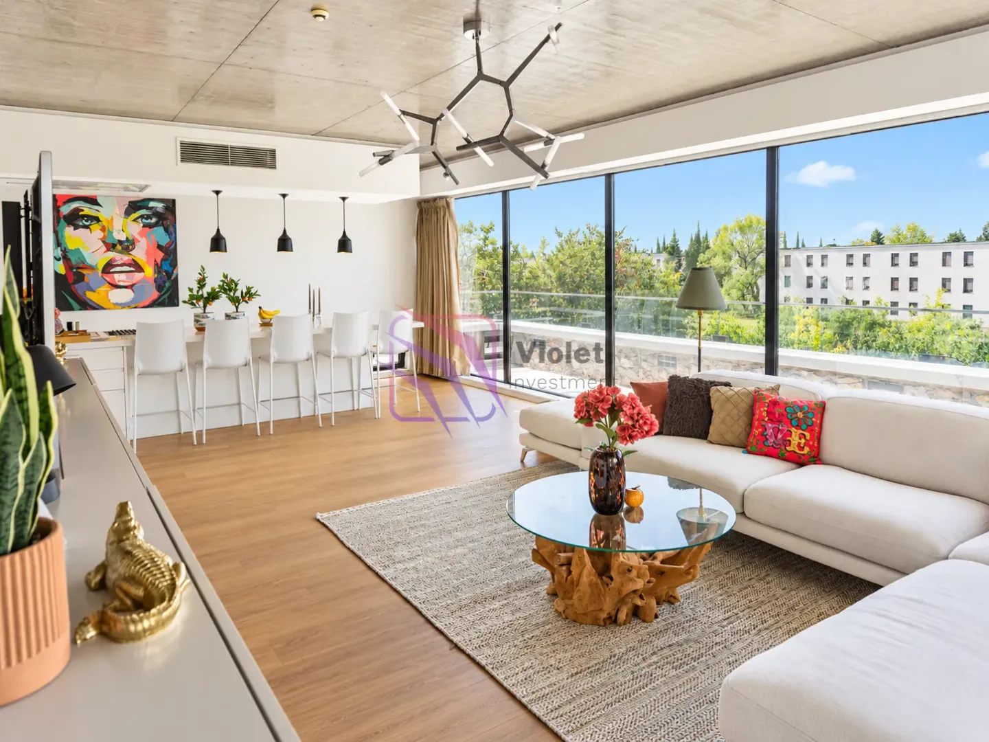 Spacious living room with dining area and large glass surfaces overlooking greenery.