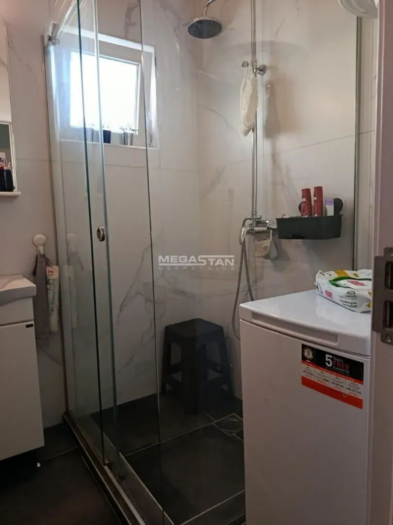 Bathroom with a glass shower enclosure and a washing machine.