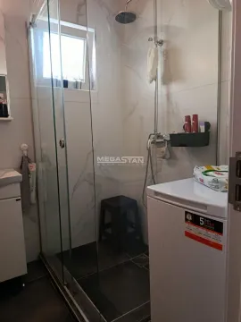 Bathroom with a glass shower enclosure and a washing machine. - image 9