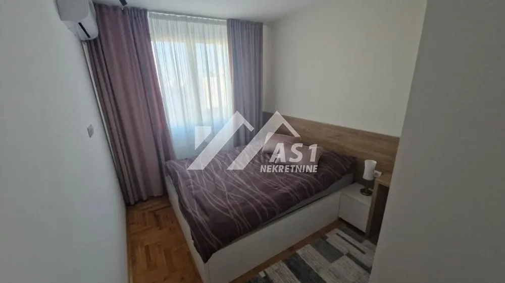 Nameštena spavaća soba sa bračnim krevetom i prozorom.