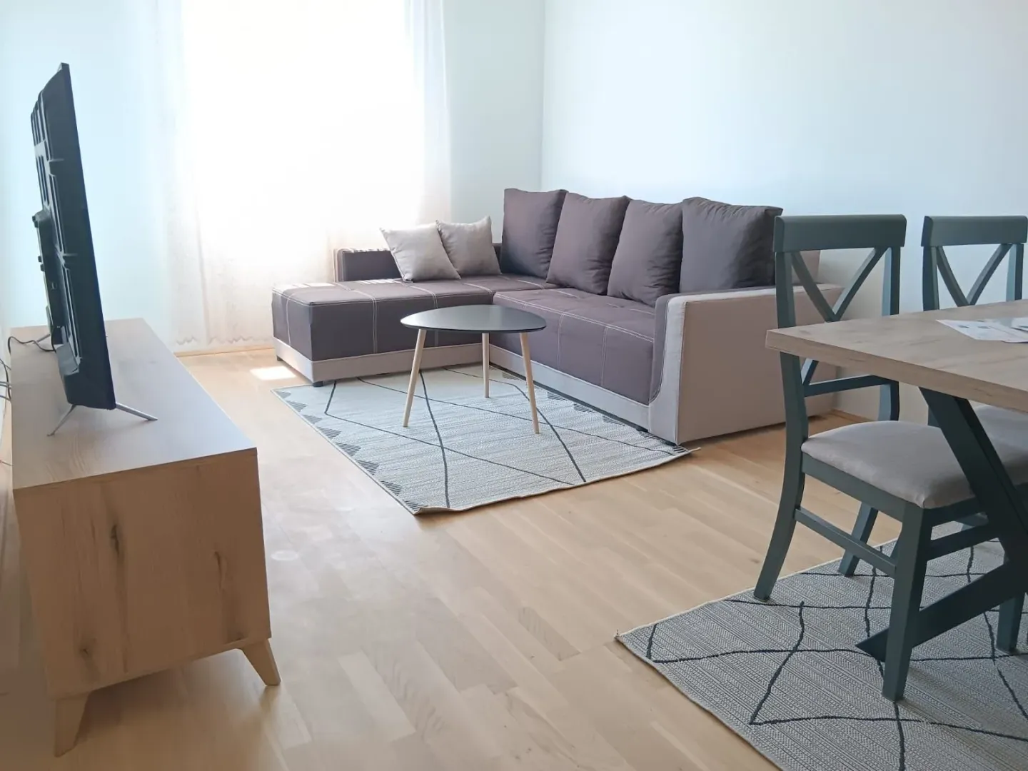 Dnevni boravak sa garniturom, TV-om i trpezarijskim stolom.