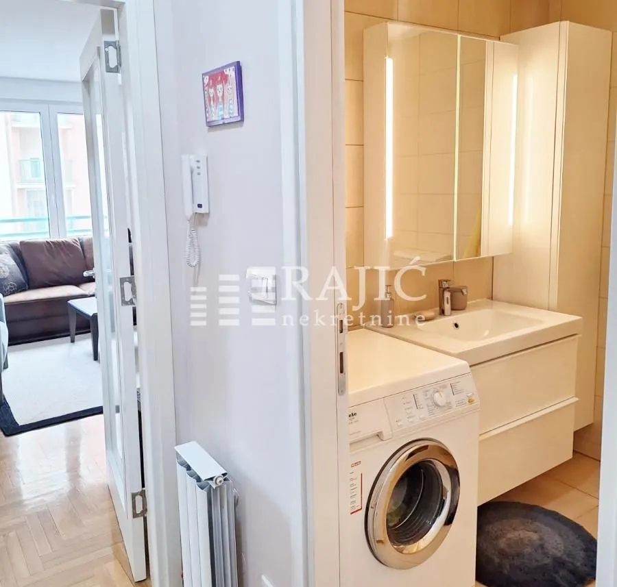 Smaller bathroom with a sink, mirror, and washing machine.