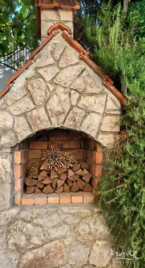 Zidani roštilj od kamena sa drvima za potpalu u dvorištu.