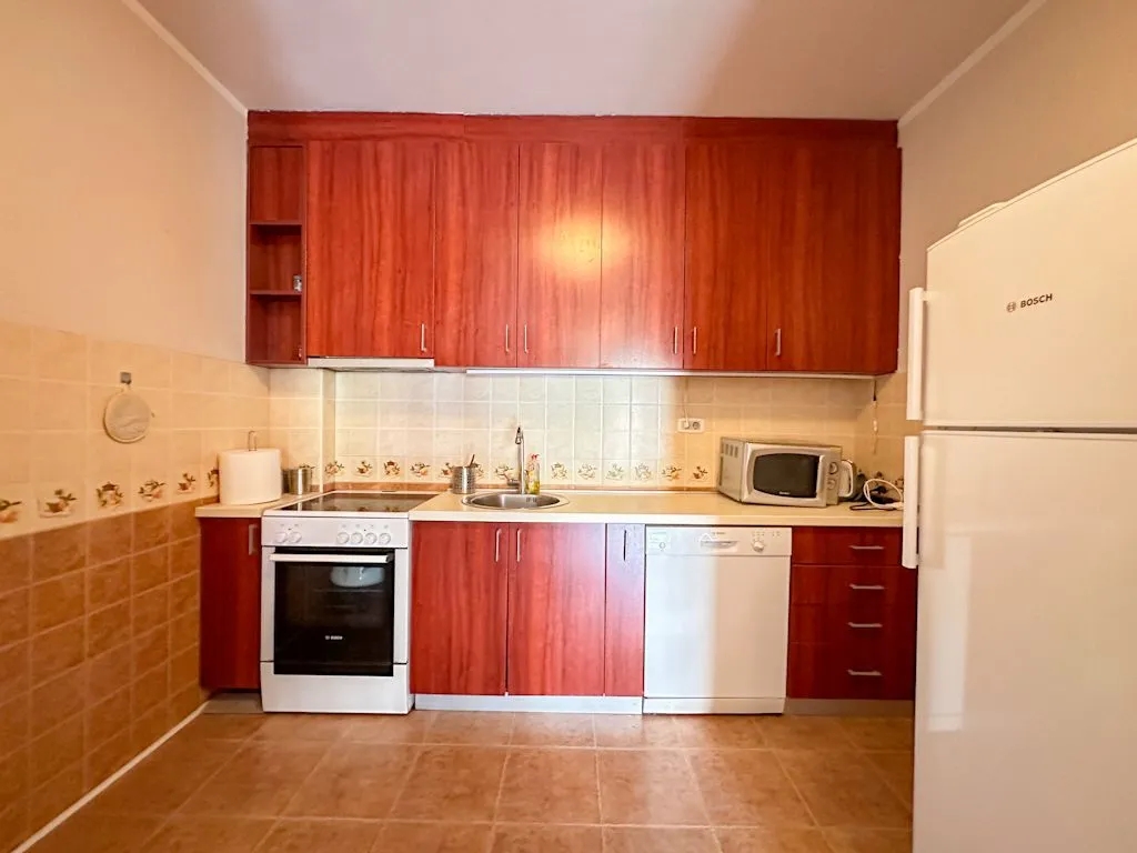 Kuhinja opremljena drvenim elementima i ugrađenim kućnim aparatima.