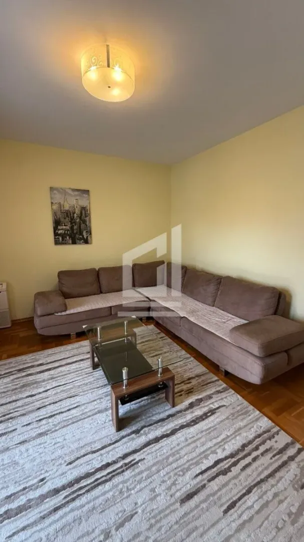 Living room with a sectional sofa, a glass coffee table, and a rug.