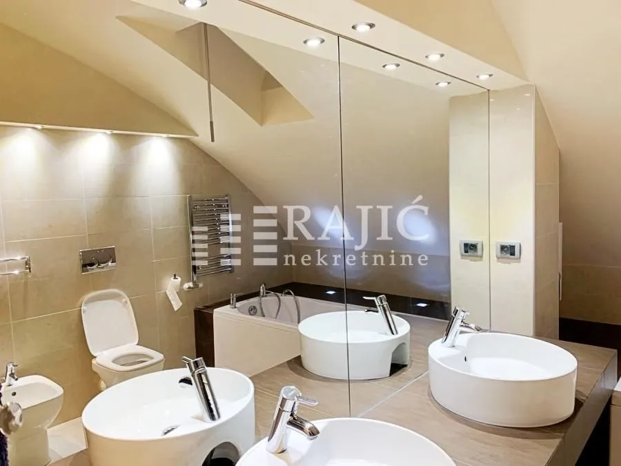 Modern bathroom with two sinks, a bathtub, and recessed lighting.