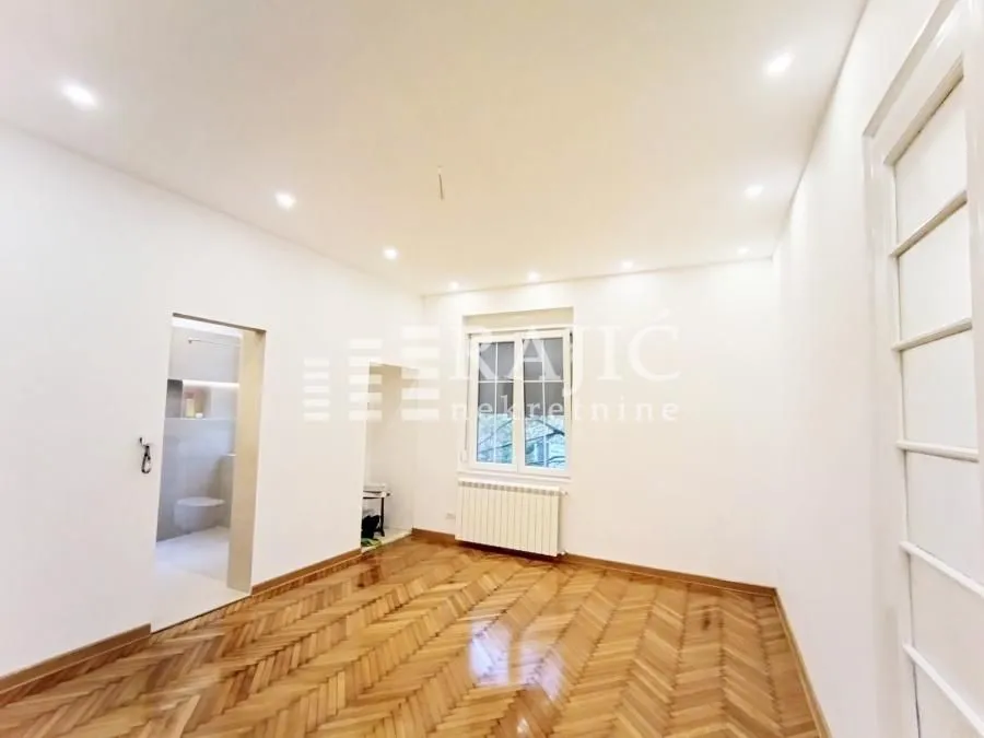 Empty room with parquet flooring and white walls.