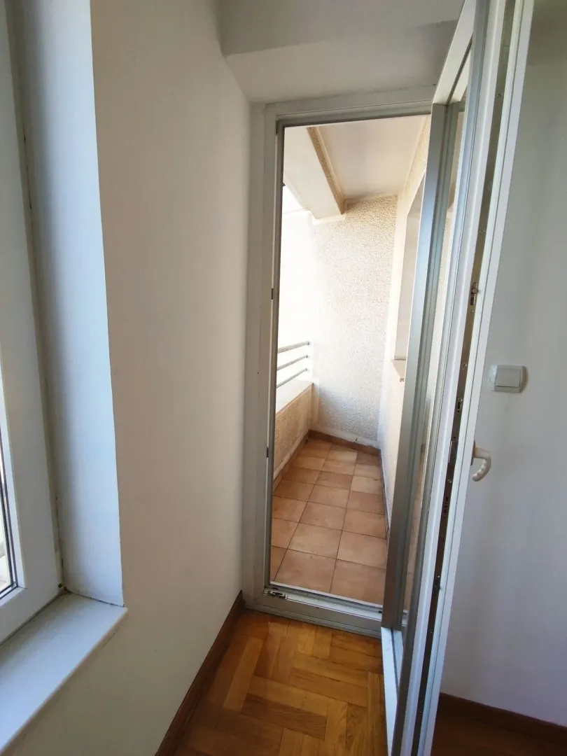 Pogled iz prostorije na popločanu terasu sa balkonskim vratima.
