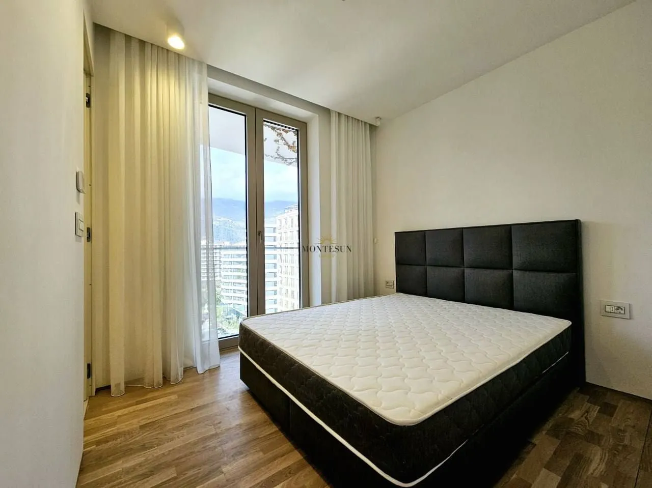 Modern bedroom with a double bed and large balcony doors.