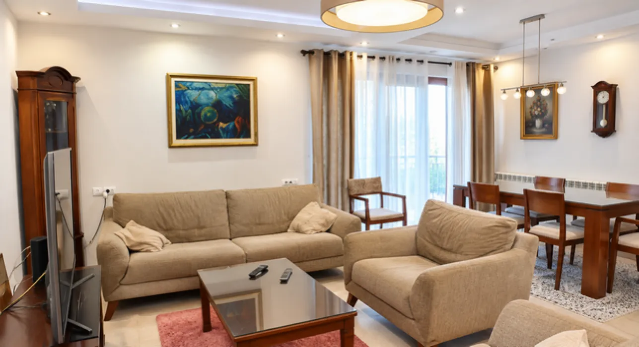 Living room with a sofa set, coffee table, and dining area in the background.