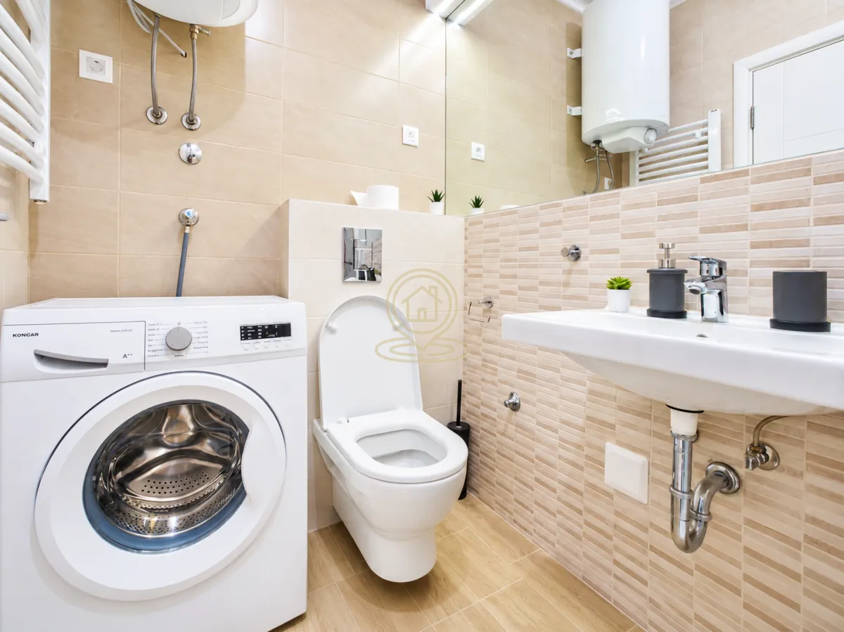 Kompaktno kupatilo sa tuš kabinom, umivaonikom i WC šoljom u bež tonovima.