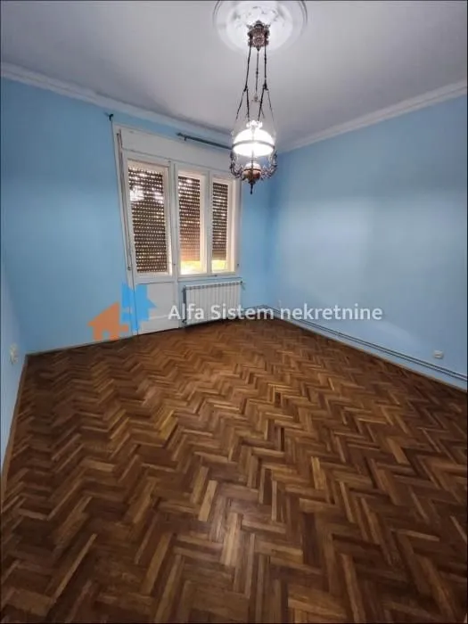 Empty room with blue walls and herringbone parquet flooring.