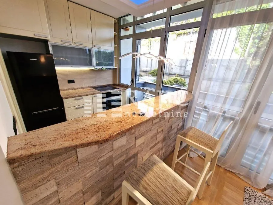 Modern kitchen with a bar counter and bar stools by a large window.