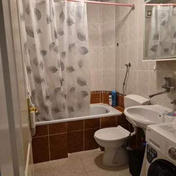 Smaller bathroom with a bathtub, washbasin, toilet, and washing machine. - image 9