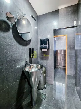 Modern bathroom equipped with dark tiles, a washbasin, and a round mirror. - image 17