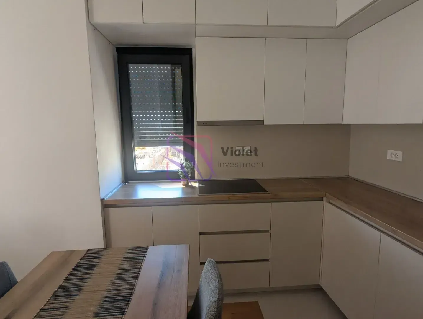 Modern kitchen with white units and a dining table.
