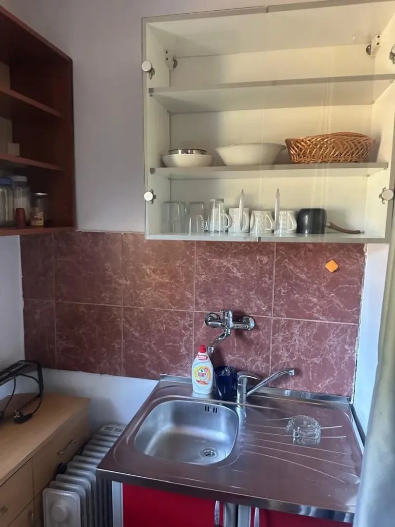 Manja kuhinja sa sudoperom, slavinom i visećim elementima.