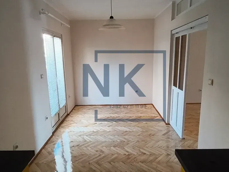 Empty room with parquet flooring and balcony doors.