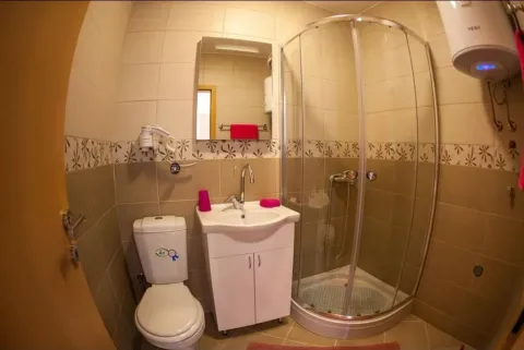 Small bathroom with a shower cabin, sink, and toilet. - image 11