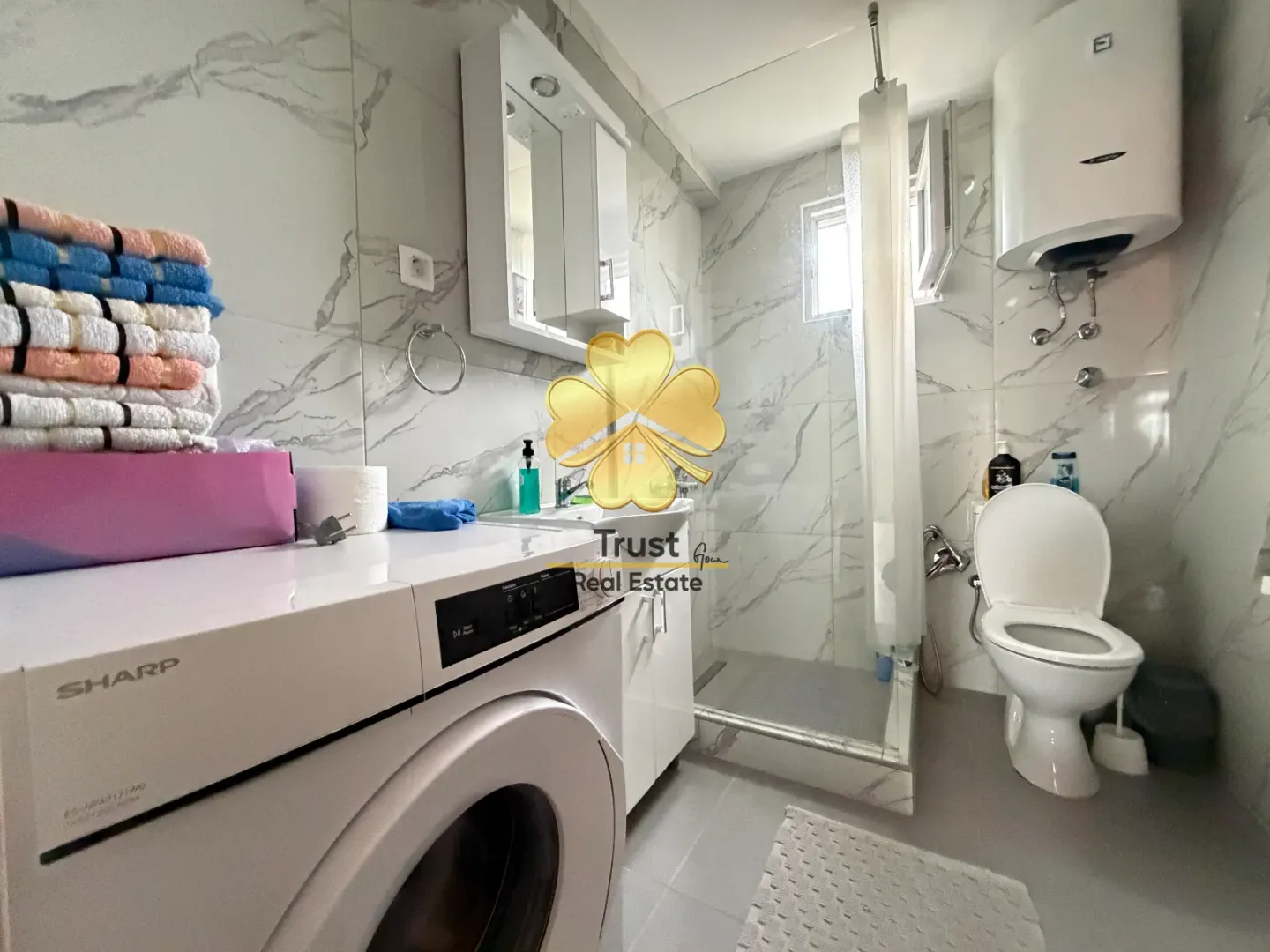Modernly equipped bathroom with washing machine and shower cabin.