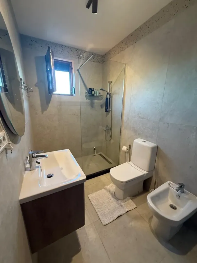 Moderne uređeno kupatilo sa tuš kabinom, umivaonikom i toaletnim elementima.