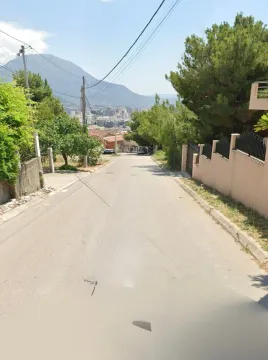 Pogled na ulicu i okolno naselje sa brdima u pozadini. - image 2
