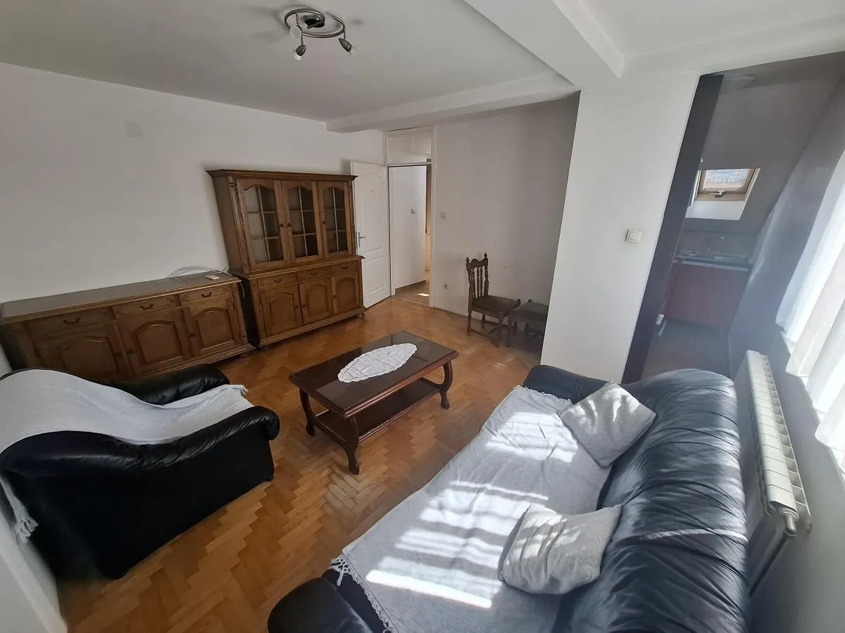 Dnevna soba sa garniturom za sedenje i drvenim nameštajem.