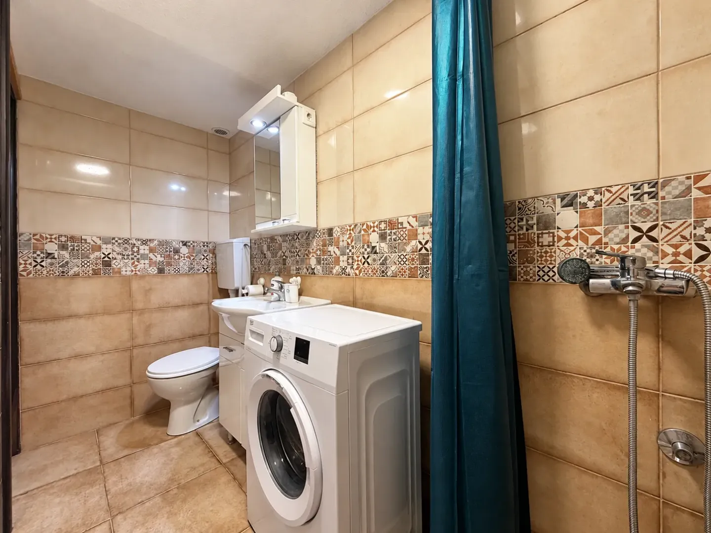 Small bathroom with a washing machine, washbasin, and shower.