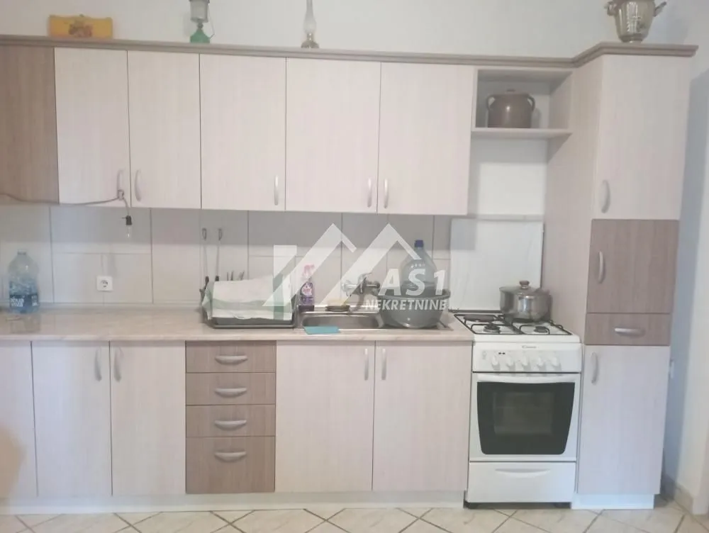 Manja kuhinja sa svetlim drvenim elementima i samostojećim štednjakom.