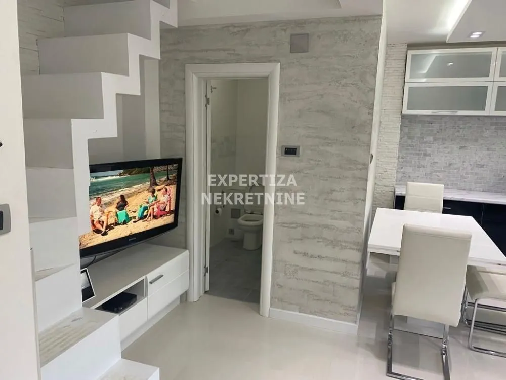 Living room with dining area, staircase, and a view of the bathroom.