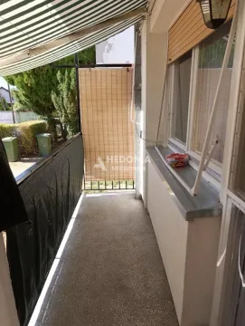 Pogled na natkriveni balkon sa zaštitom od sunca i zelenilom u pozadini. - image 12