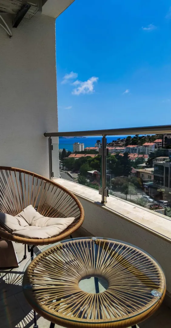 Furnished balcony with seating set and a view of the sea and city.