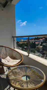 Furnished balcony with seating set and a view of the sea and city. - image 7