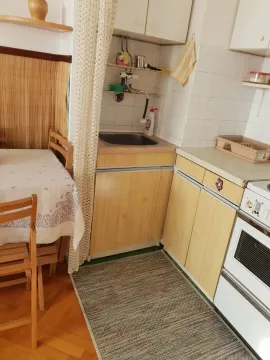 Mala funkcionalna kuhinja sa trpezarijskim stolom i drvenim elementima. - image 8