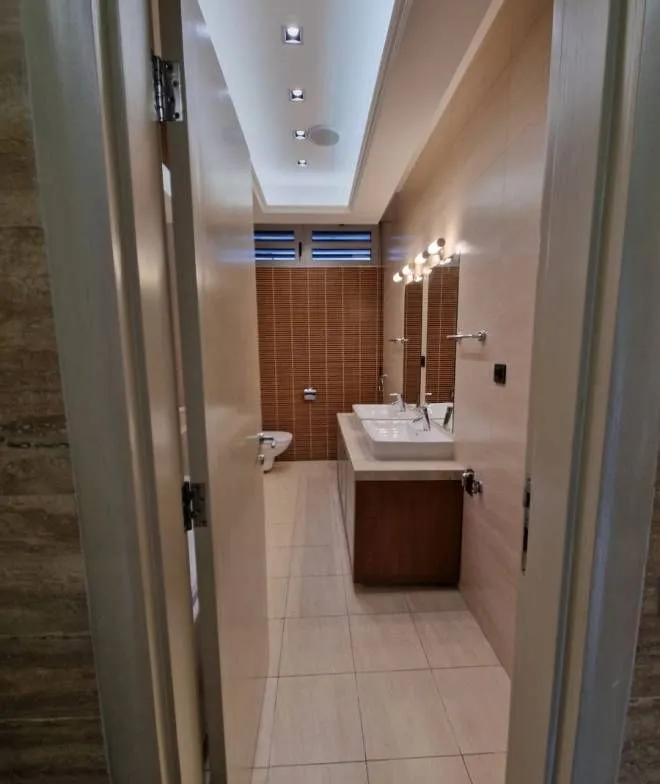 View from the hallway into a spacious bathroom with a double sink and toilet.