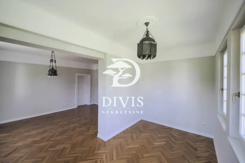Empty living room with parquet flooring and traditional chandeliers.