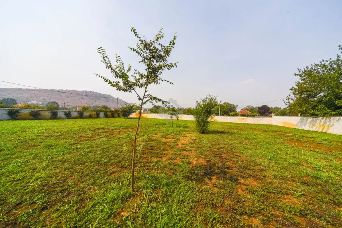 View of the spacious yard and lawn enclosed by a wall.