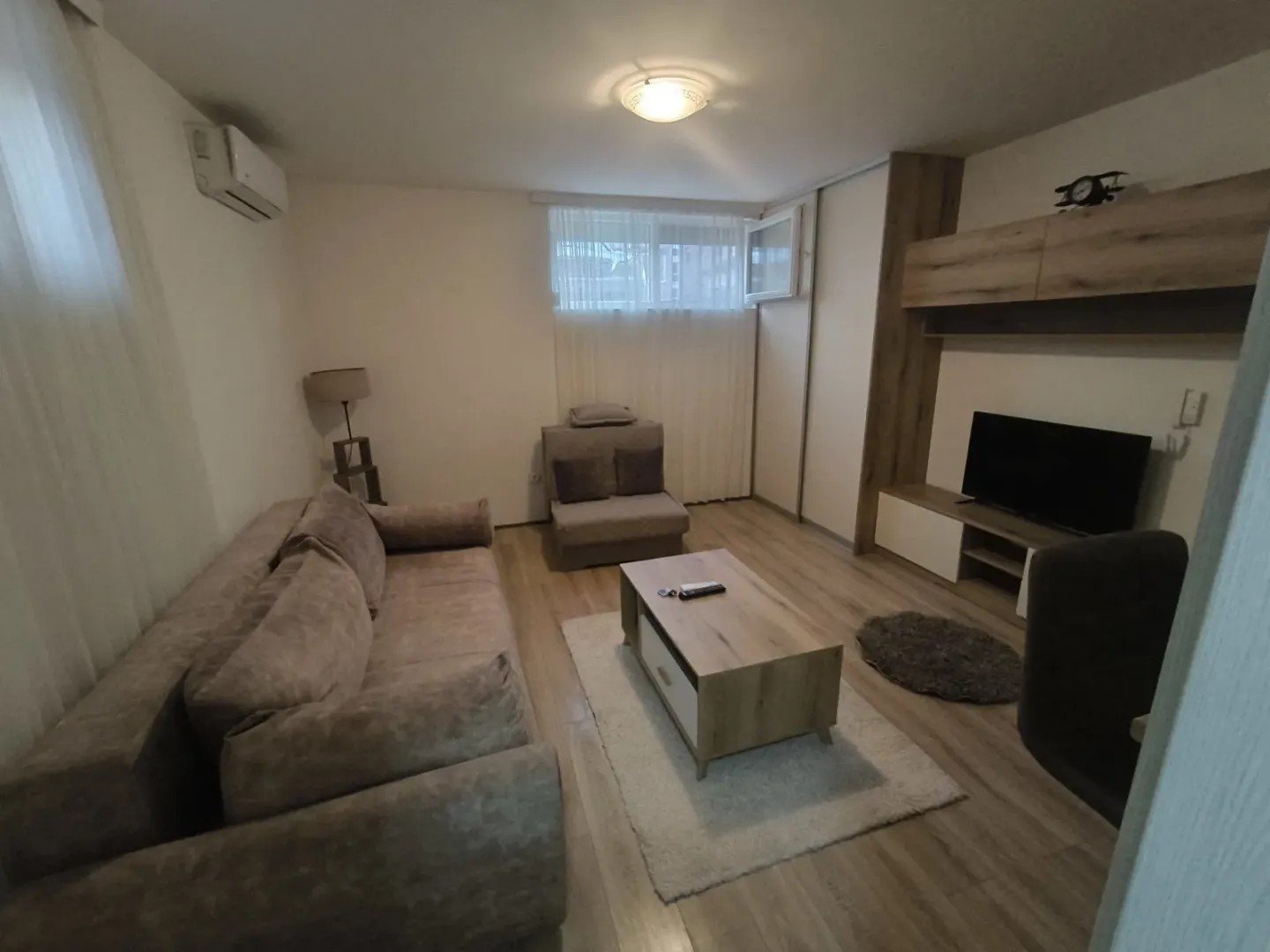 A bright living room with modern furniture, a coffee table, and a television.