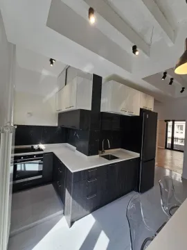 Modern kitchen with black units and white countertops. - image 2