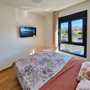 Spavaća soba sa bračnim krevetom, televizorom na zidu i prozorom sa pogledom na okolinu. - image 5