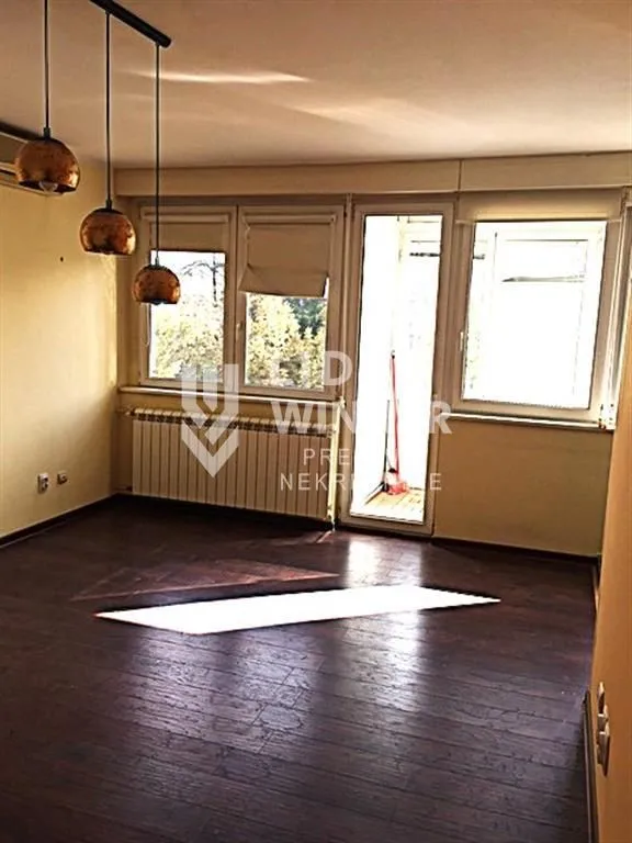 Empty living room with dark parquet flooring and hanging lamps.