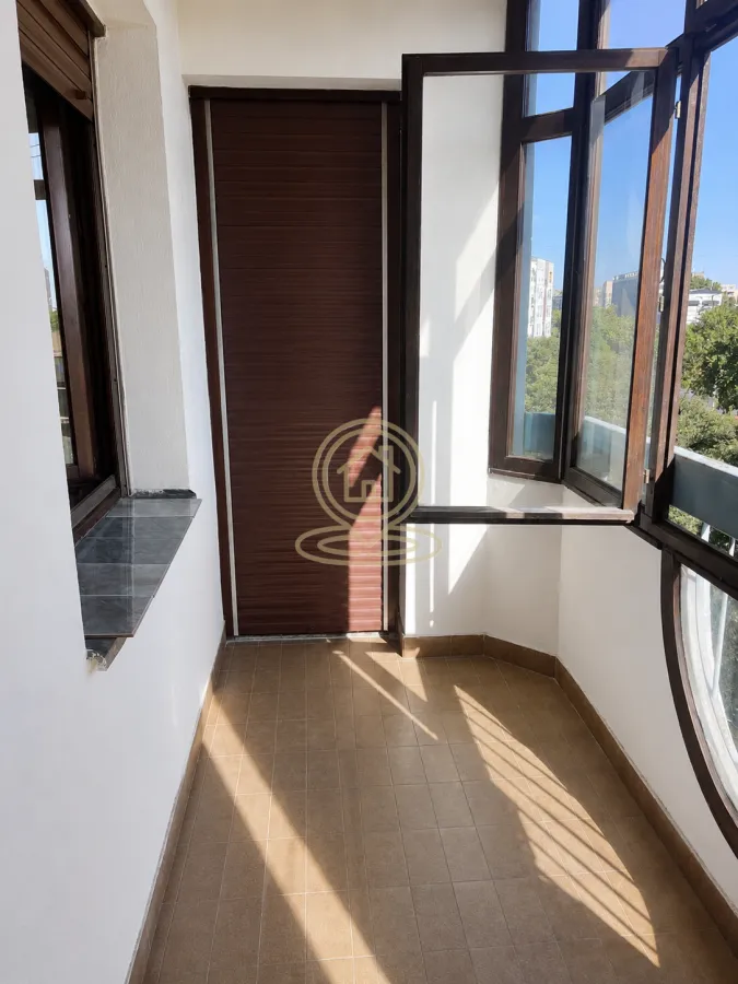 Zastakljeni balkon sa keramičkim pločicama na podu i drvenom stolarijom.